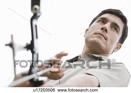 Stock Photograph - Mid adult man with bow and arrow (low angle view). Fotosearch