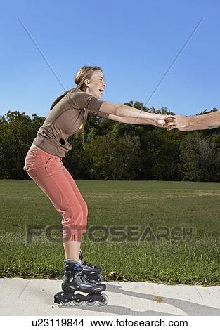 Mid Adult Woman Rollerblading and Holding Person's Hands View Large Photo Image Picture - Mid Adult Woman Rollerblading and Holding Person's Hands. Fotosearch