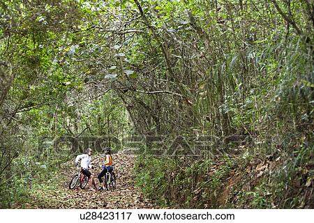 Stock Photo - Two cyclists talking in forest. Fotosearch
