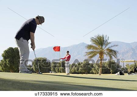 Stock Photography - Two people playing golf at golf course. Fotosearch