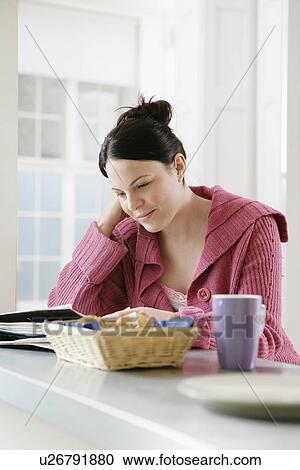 Mid adult woman reading magazine at kitchen counter View Large Photo Image Stock Image - Mid adult woman reading magazine at kitchen counter. Fotosearch