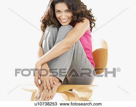 Stock Image - Woman sitting on chair and smiling (portrait). Fotosearch