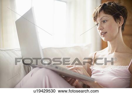 Woman using laptop computer on sofa View Large Photo Image Stock Image - Woman using laptop computer on sofa. Fotosearch