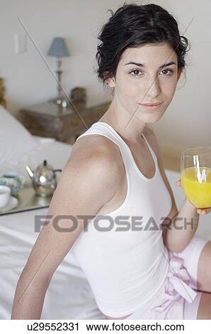 Young woman drinking orange juice on bed (portrait) View Large Photo Image Stock Image - Young woman drinking orange juice on bed (portrait). Fotosearch
