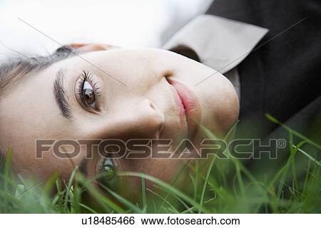 Woman lying on grass (portrait, low angle view) View Large Photo Image Stock Photograph - Woman lying on grass (portrait, low angle view). Fotosearch