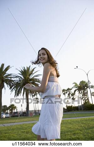 Picture - Young adult woman looking back and smiling, Side View, Low Angle View, Differential Focus. Fotosearch