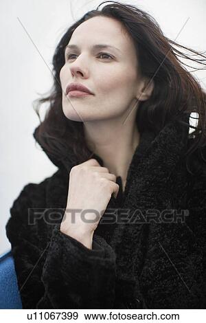 Young woman holding her coat (portrait, low angle view) View Large Photo Image Stock Photo - Young woman holding her coat (portrait, low angle view). Fotosearch