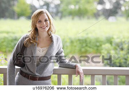 Young woman leaning on banister (portrait) View Large Photo Image Stock Photograph - Young woman leaning on banister (portrait). Fotosearch