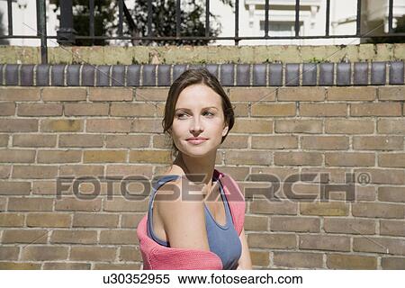 Stock Photography - Young woman near brick wall (portrait). Fotosearch