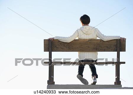 Young woman sitting on bench and looking at view (rear view) View Large Photo Image Stock Image - Young woman sitting on bench and looking at view (rear view). Fotosearch