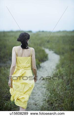 Stock Photo - Young woman walking on path (rear view). Fotosearch
