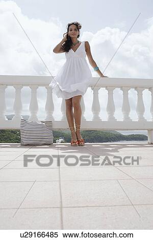 Stock Photography - Young woman with handbag standing on balcony (low angle view). Fotosearch