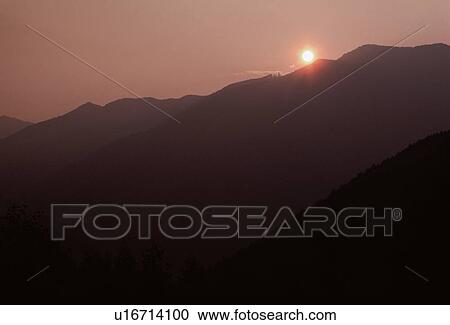 Stock Image - Sun Setting Behind Mountains. Fotosearch