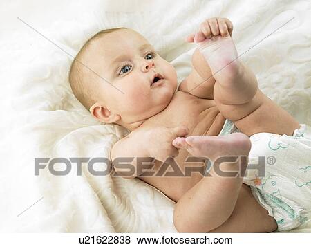 Baby lying down holding foot View Large Photo Image Stock Photo - Baby lying down holding foot. Fotosearch