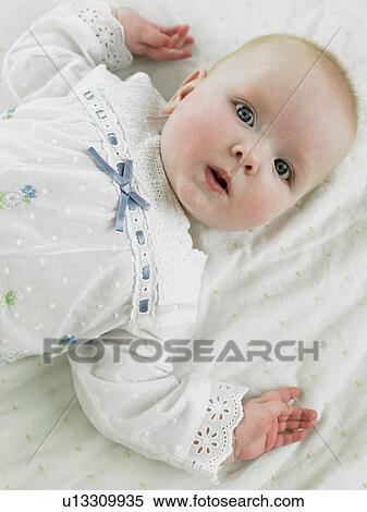 Baby lying on back looking at camera View Large Photo Image Stock Photography - Baby lying on back looking at camera. Fotosearch