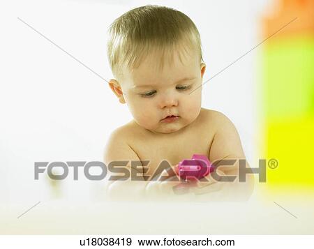 Stock Photo - Baby playing with plastic block. Fotosearch