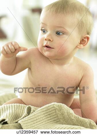 Stock Photo - Baby sitting by a sweater looking at hand. Fotosearch