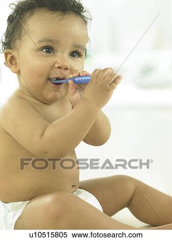 Stock Photography - Baby sitting with toothbrush in mouth. Fotosearch