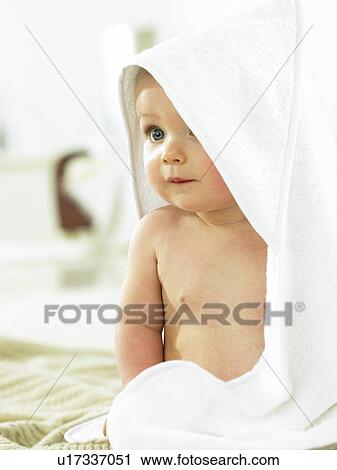 Stock Image - Baby sitting with towel over head. Fotosearch
