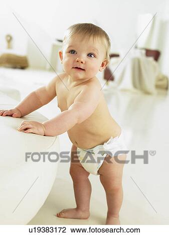 Baby standing indoors holding couch View Large Photo Image Stock Image - Baby standing indoors holding couch. Fotosearch