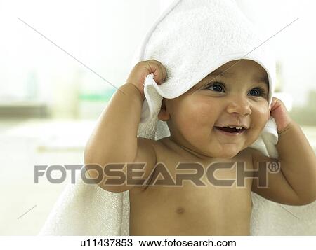 Stock Image - Baby with towel over head smiling. Fotosearch