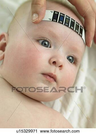 Stock Image - Baby lying down taking temperature. Fotosearch