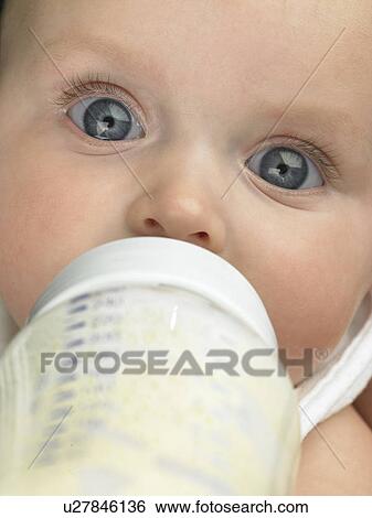 Stock Photograph - Baby's face close up with baby bottle. Fotosearch
