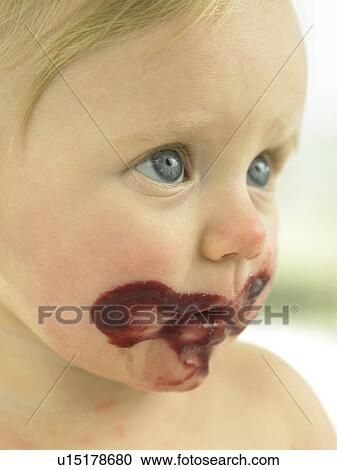 Stock Image - Baby's face close up with chocolate mess on face. Fotosearch
