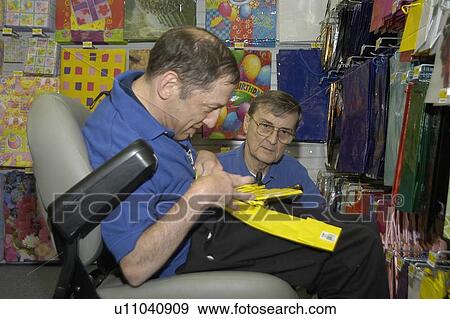 A man with a disability, utilizing a wheelchair for mobility, getting assistance stocking a store. View Large Photo Image Stock Photo - A man with a disability, utilizing a wheelchair for mobility, getting assistance stocking a store.. Fotosearch