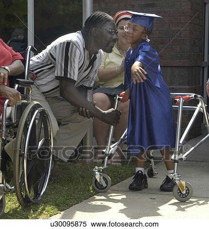A precious moment between a father and his daughter, who has disabilities and utilizes a walker for mobility assistance, as she prepares to participate in her preschool graduation. View Large Photo Image Stock Photography - A precious moment between a father and his daughter, who has disabilities and utilizes a walker for mobility assistance, as she prepares to participate in her preschool graduation.. Fotosearch