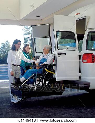 Picture - Elderly woman with a disability being lifted into a van to get where she wants to go.. Fotosearch