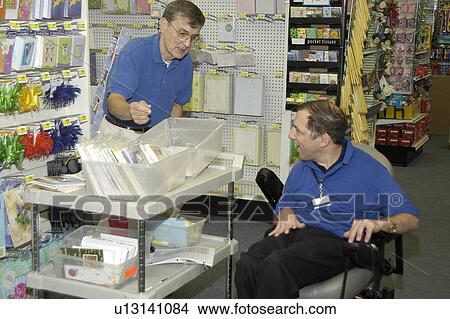 Man with a disability, utilizing a wheelchair for mobility, enjoying an afternoon working in a store. View Large Photo Image Picture - Man with a disability, utilizing a wheelchair for mobility, enjoying an afternoon working in a store.. Fotosearch