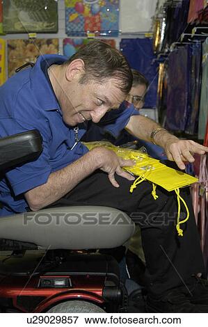 Man with a disability, utilizing a wheelchair for mobility, enjoying an afternoon working in a store. View Large Photo Image Stock Photo - Man with a disability, utilizing a wheelchair for mobility, enjoying an afternoon working in a store.. Fotosearch