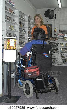 Man with a disability, utilizing a wheelchair for mobility, entering a video store. View Large Photo Image Stock Photography - Man with a disability, utilizing a wheelchair for mobility, entering a video store.. Fotosearch