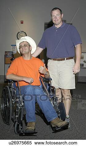Stock Photography - Man with a disability, utilizing a wheelchair for mobility, enjoy an afternoon with his friend.. Fotosearch