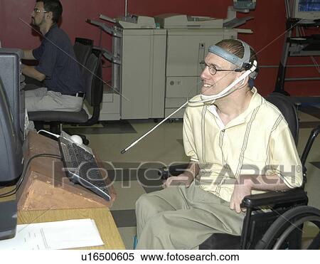 Stock Photography - Man with significant disabilities utilizing headgear to operate communications apparatus.. Fotosearch
