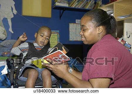 Student with a disability receiving assistance from his teacher to read a book. View Large Photo Image Stock Image - Student with a disability receiving assistance from his teacher to read a book.. Fotosearch