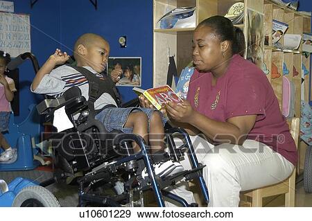 Student with a disability receiving assistance from his teacher to read a book. View Large Photo Image Stock Photo - Student with a disability receiving assistance from his teacher to read a book.. Fotosearch