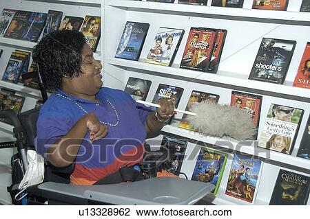 Woman with a disability at work in a video rental store. View Large Photo Image Stock Image - Woman with a disability at work in a video rental store.. Fotosearch