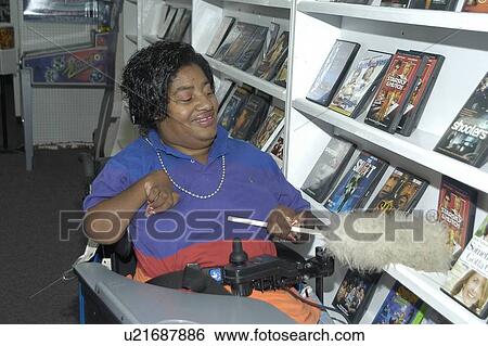 Woman with a disability at work in a video rental store. View Large Photo Image Stock Photograph - Woman with a disability at work in a video rental store.. Fotosearch