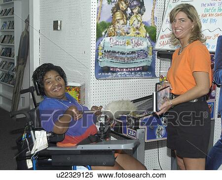 Woman with a disability at work in a video rental store. View Large Photo Image Stock Photography - Woman with a disability at work in a video rental store.. Fotosearch