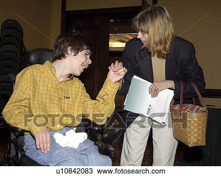 Stock Image - Young man with significant disabilities spending time with a friend.. Fotosearch