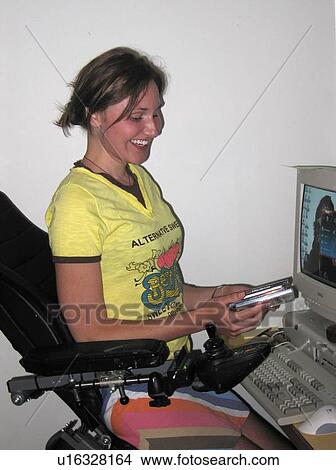 Young woman (wheelchair user) laughs as she reviews software at her computer. View Large Photo Image Picture - Young woman (wheelchair user) laughs as she reviews software at her computer.. Fotosearch