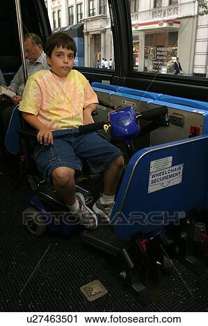 Stock Image - Boy using a scooter/cart for mobility traveling on a city bus.. Fotosearch