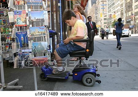 Boy using a scooter/cart purchasing a post card on the streets of New York City. View Large Photo Image Stock Photo - Boy using a scooter/cart purchasing a post card on the streets of New York City.. Fotosearch