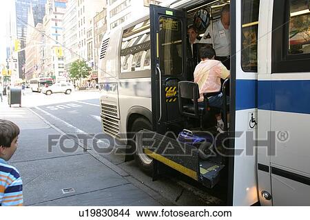 Picture - Boy with Muscular Dystrophy, utilizing a scooter/cart for mobility, exiting a city bus via a chair lift.. Fotosearch