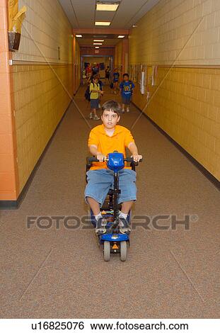 Boy with Muscular Dystrophy, utilizing a scooter/cart for mobility, heading down the school hallway to get to his next class. View Large Photo Image Stock Photograph - Boy with Muscular Dystrophy, utilizing a scooter/cart for mobility, heading down the school hallway to get to his next class.. Fotosearch