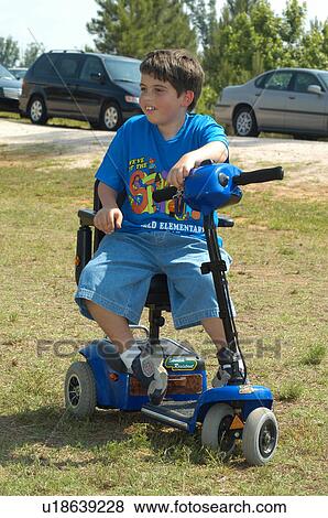 Cute boy with a disability, utilizing a scooter for mobility, spending some time outside. View Large Photo Image Stock Photo - Cute boy with a disability, utilizing a scooter for mobility, spending some time outside.. Fotosearch