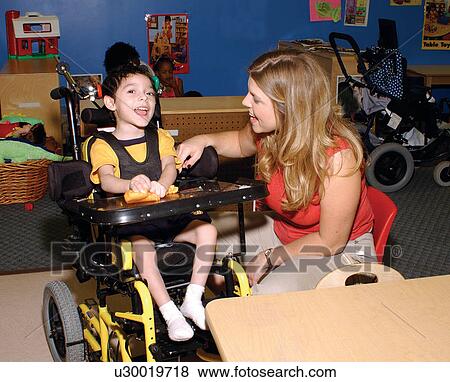 Cute little boy with multiple disabilities interacting with his teacher during a lesson at his school. View Large Photo Image Stock Photo - Cute little boy with multiple disabilities interacting with his teacher during a lesson at his school.. Fotosearch