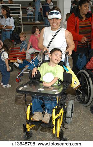 Little boy with a disability, utilizing a wheelchair for mobility, attending an event with his family. View Large Photo Image Stock Photo - Little boy with a disability, utilizing a wheelchair for mobility, attending an event with his family.. Fotosearch